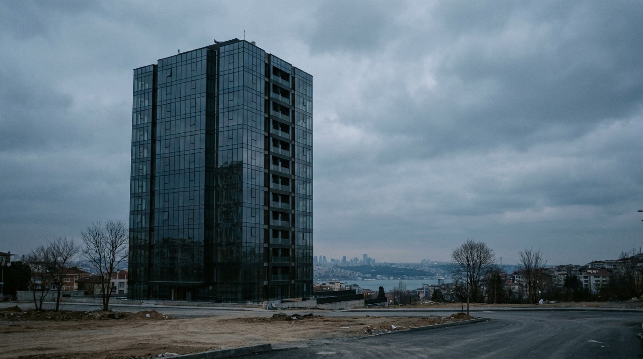 İstanbul'da gökdelen silüetinde yükselen cam cepheli markalı rezidans kulesi, boğucu bir mavi gökyüzü altında